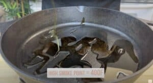 Oil being poured into a cast iron skillet with High Smoke Point = 400F text displayed.